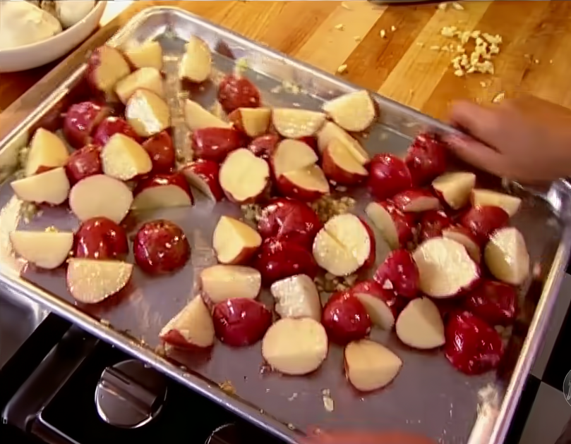 Halved petite red potatoes with garlic on a baking sheet ready for roasting