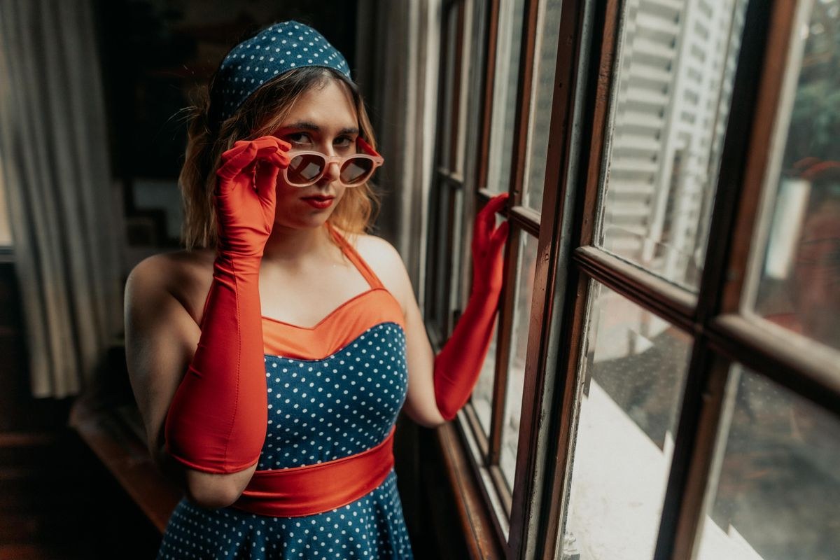 Woman in a retro polka dot dress with red gloves and sunglasses