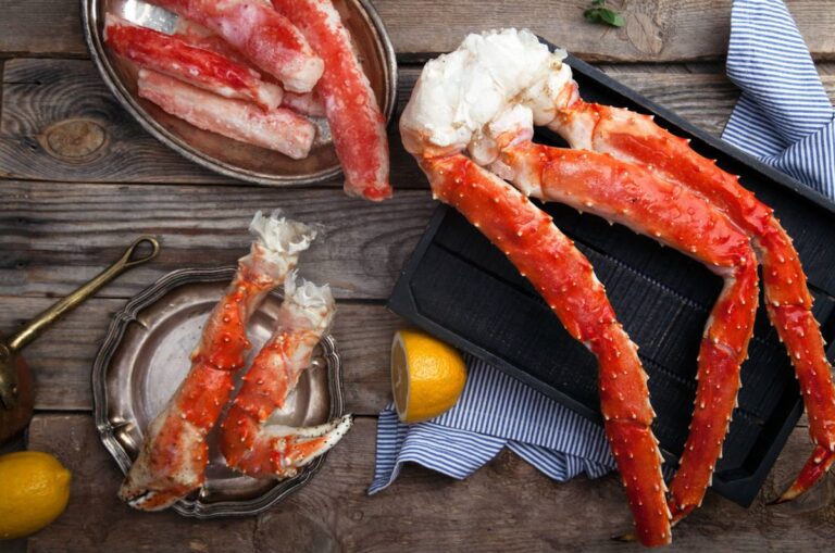 Cooked snow crab legs with lemon on a wooden board