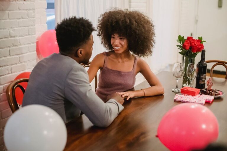 Couple celebrating at a restaurant table with roses and a gift