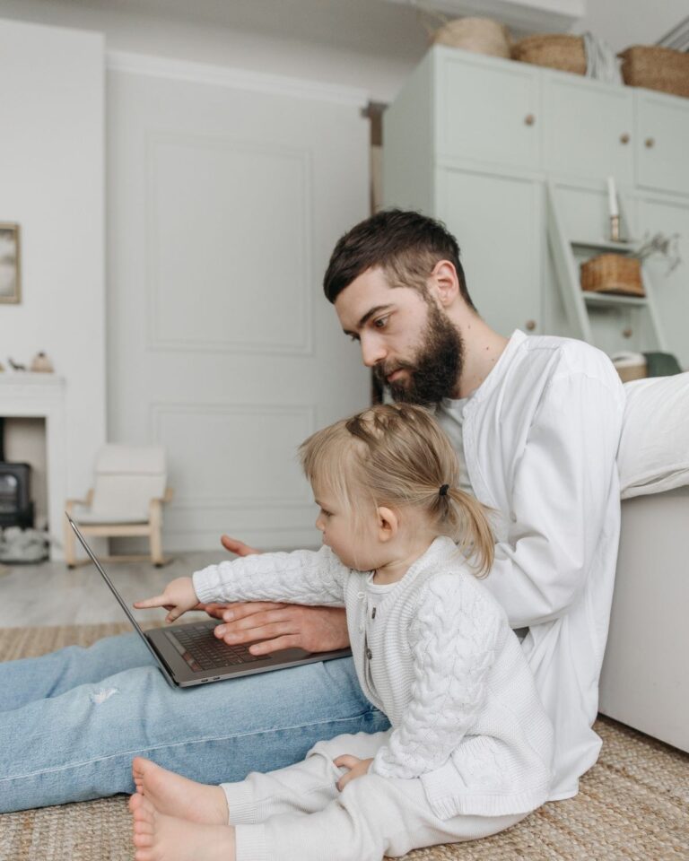 Father working on a laptop at home with his young daughter
