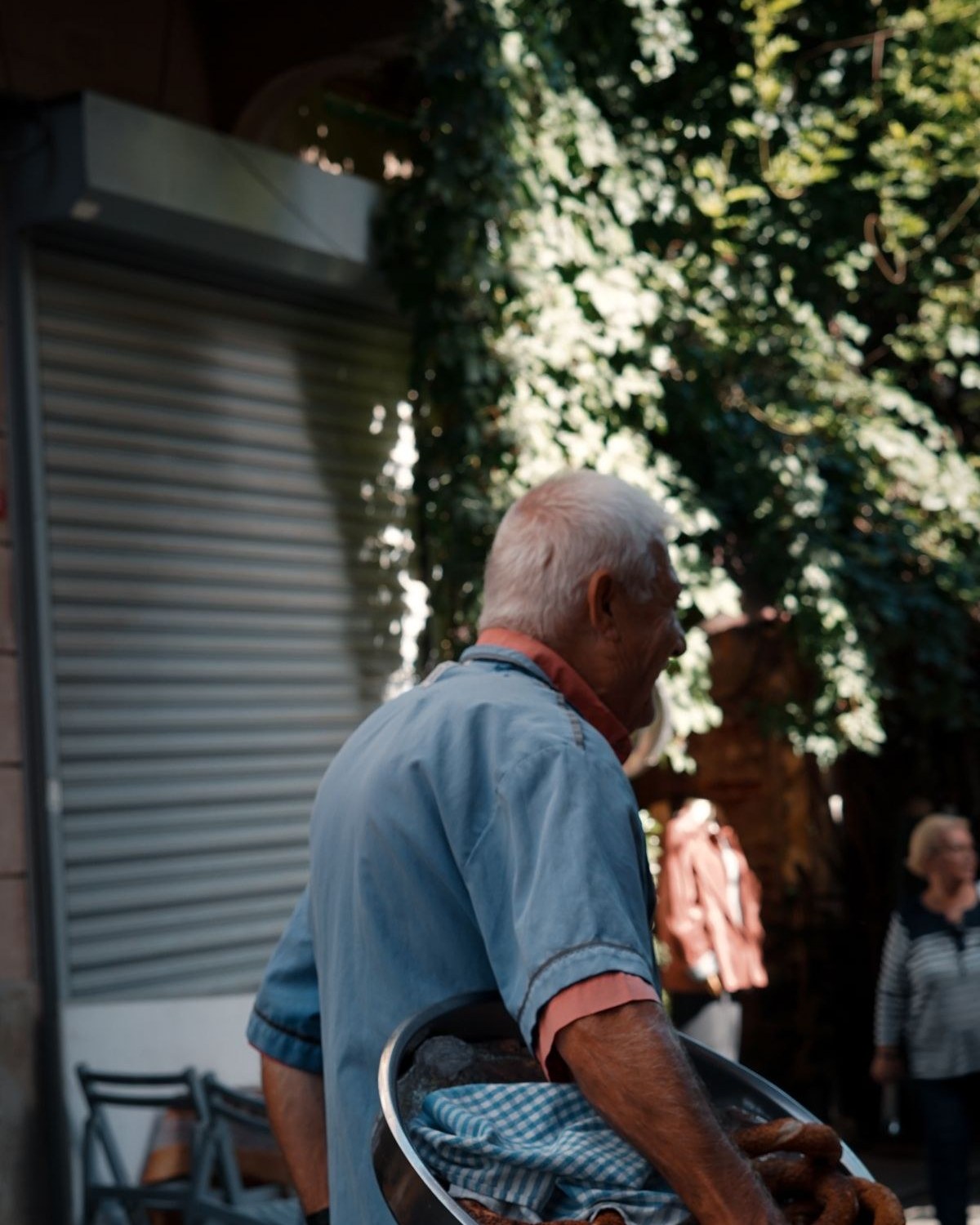 Elderly man carrying a tray of pastries on a street